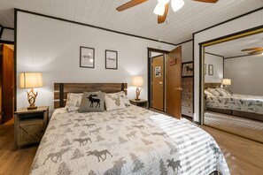 Une chambre à coucher avec un grand lit, deux tables de chevet avec des lampes, une tête de lit en bois et un miroir au mur.