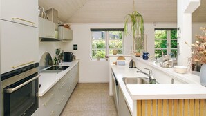 Eine moderne Küche mit weißen Schränken, einem eingebauten Backofen und einem großen Fenster für natürliches Licht.