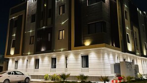 A modern multi-story building with illuminated windows and a white facade.