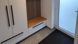 A modern room with white cabinets, a wooden bench, and a sliding glass door.