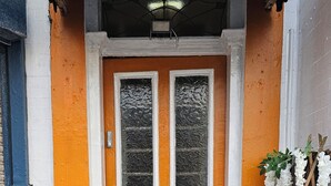 Ein Haus mit einer leuchtend orangefarbenen Tür, weißem Zierwerk und einem kleinen Ziegelaufgang.