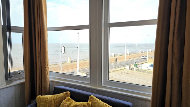 Ein Zimmer mit großem Fenster, Blick auf Strand und Straße.