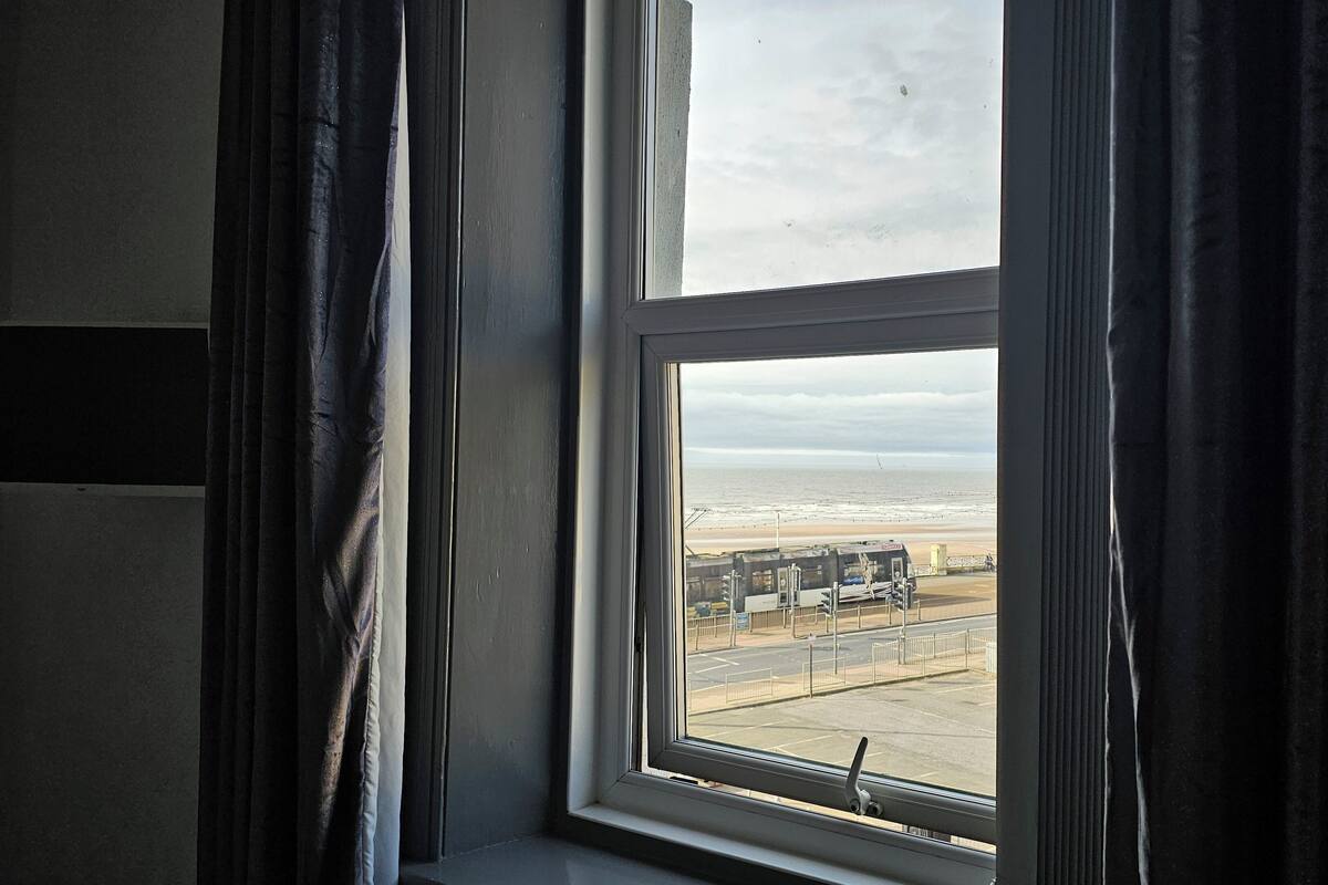 Una ventana con vista a una playa y un estacionamiento.