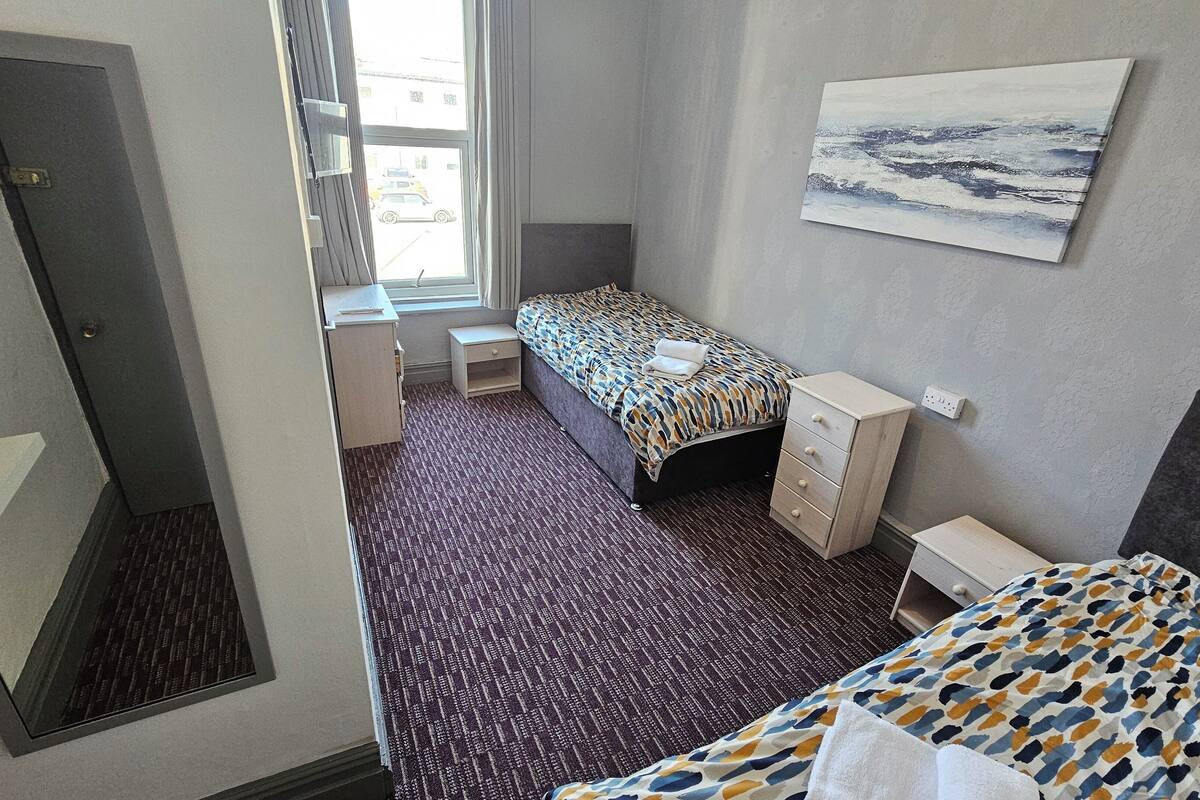 Habitación de hotel con cama, escritorio, silla, cómoda y ventana con vistas al exterior.