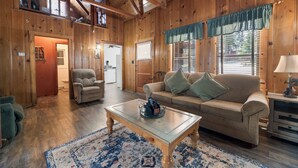 L’intérieur d’un chalet accueillant, avec un plancher en bois, un canapé, un fauteuil et une table basse.