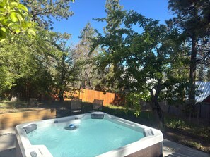 A hot tub in a backyard with trees and a wooden fence. - Chalet Des Ours (Big Bear Lake)