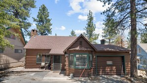Une cabane en rondins avec un garage, une véranda et une cheminée.
