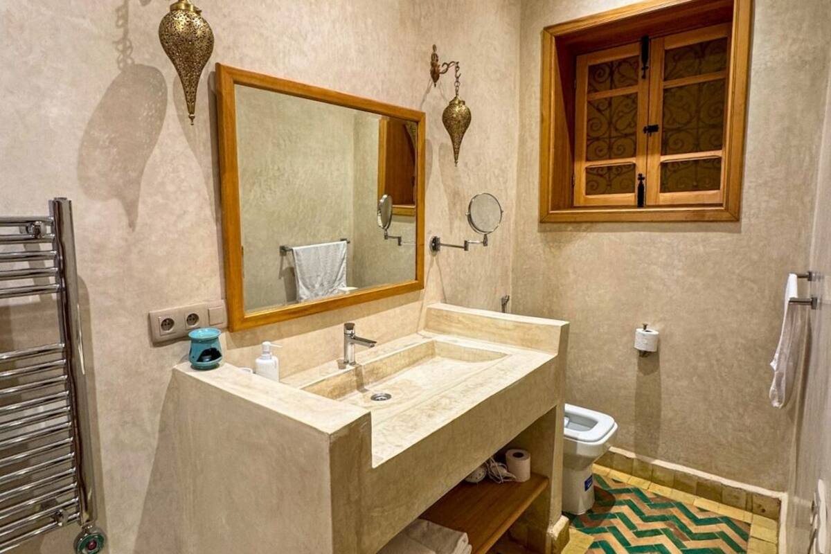 A bathroom with two sinks, a large mirror, a toilet, and a patterned floor.