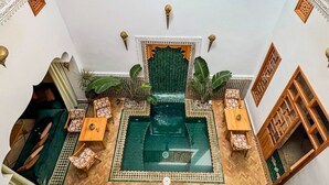 Une pièce spacieuse avec une piscine centrale verdoyante, un tapis décoratif suspendu et différents types de sièges.
