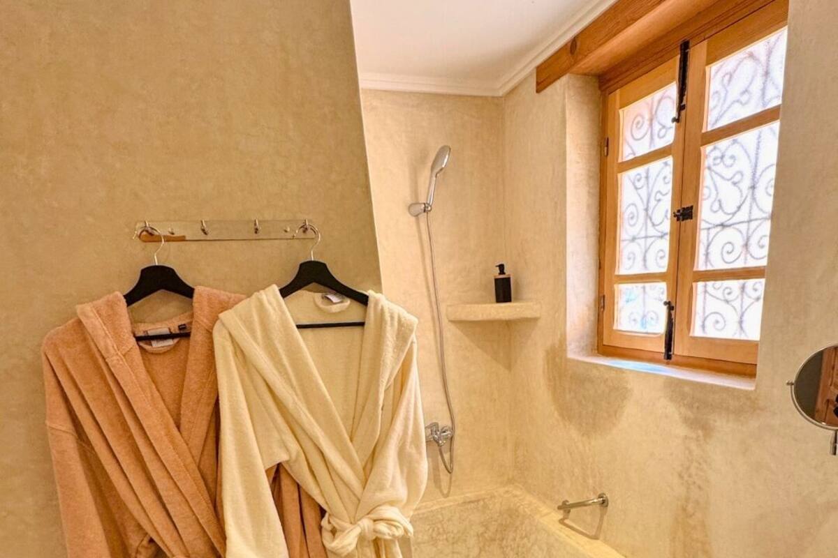 A bathroom with a bathtub, a shower, and a window with decorative iron bars.