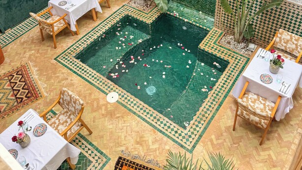 Une cour avec une piscine, des espaces aménagés pour s’asseoir et des carreaux décoratifs.