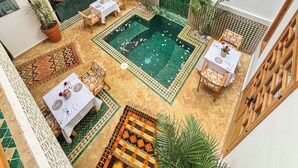 Une cour avec une piscine, des espaces aménagés pour se détendre et un coin repas.