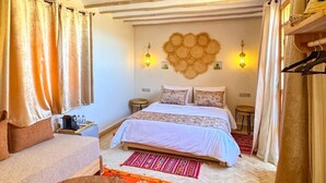 Une chambre confortable avec un lit, deux tables de chevet, une table basse en bois et un tapis rouge à motifs.