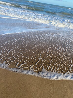 Una playa arenosa con olas suaves lamiendo la orilla.