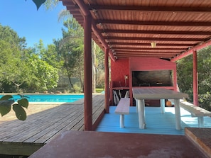 Un espace extérieur abrité comprenant une piscine, une terrasse en bois et un barbecue.