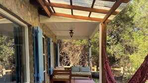 A covered patio area with a wooden deck, a hammock, and a seating area with cushions. - Marvelous  Stone House, Swimming Pool, Parrilleros, Beach & Nature. Pet-Friendly (Oceanía del Polonio)