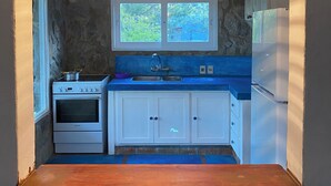 A kitchen with a stone wall, a window, a stove, a sink, and cabinets. - Marvelous  Stone House, Swimming Pool, Parrilleros, Beach & Nature. Pet-Friendly (Oceanía del Polonio)