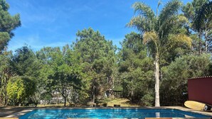 A wooden deck with lounge chairs and a swimming pool surrounded by trees. - Marvelous  Stone House, Swimming Pool, Parrilleros, Beach & Nature. Pet-Friendly (Oceanía del Polonio)