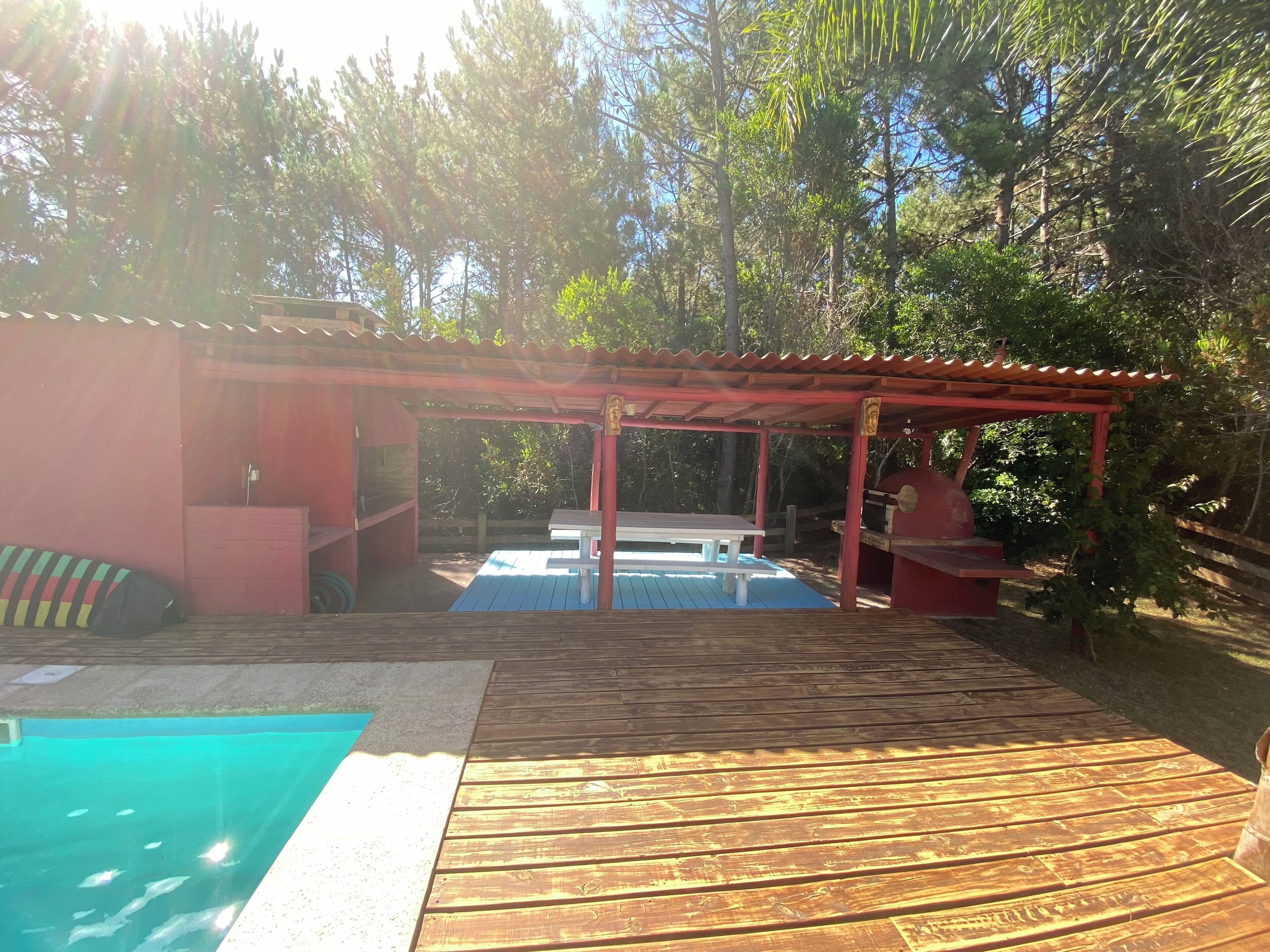 Une terrasse en bois avec une piscine, un espace barbecue et un coin salon abrité.