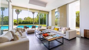 Amplia sala de estar con un ventanal grande, una piscina y un diseño interior moderno.