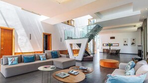 Amplia sala de estar con una escalera moderna, un conjunto de sofás y un comedor.