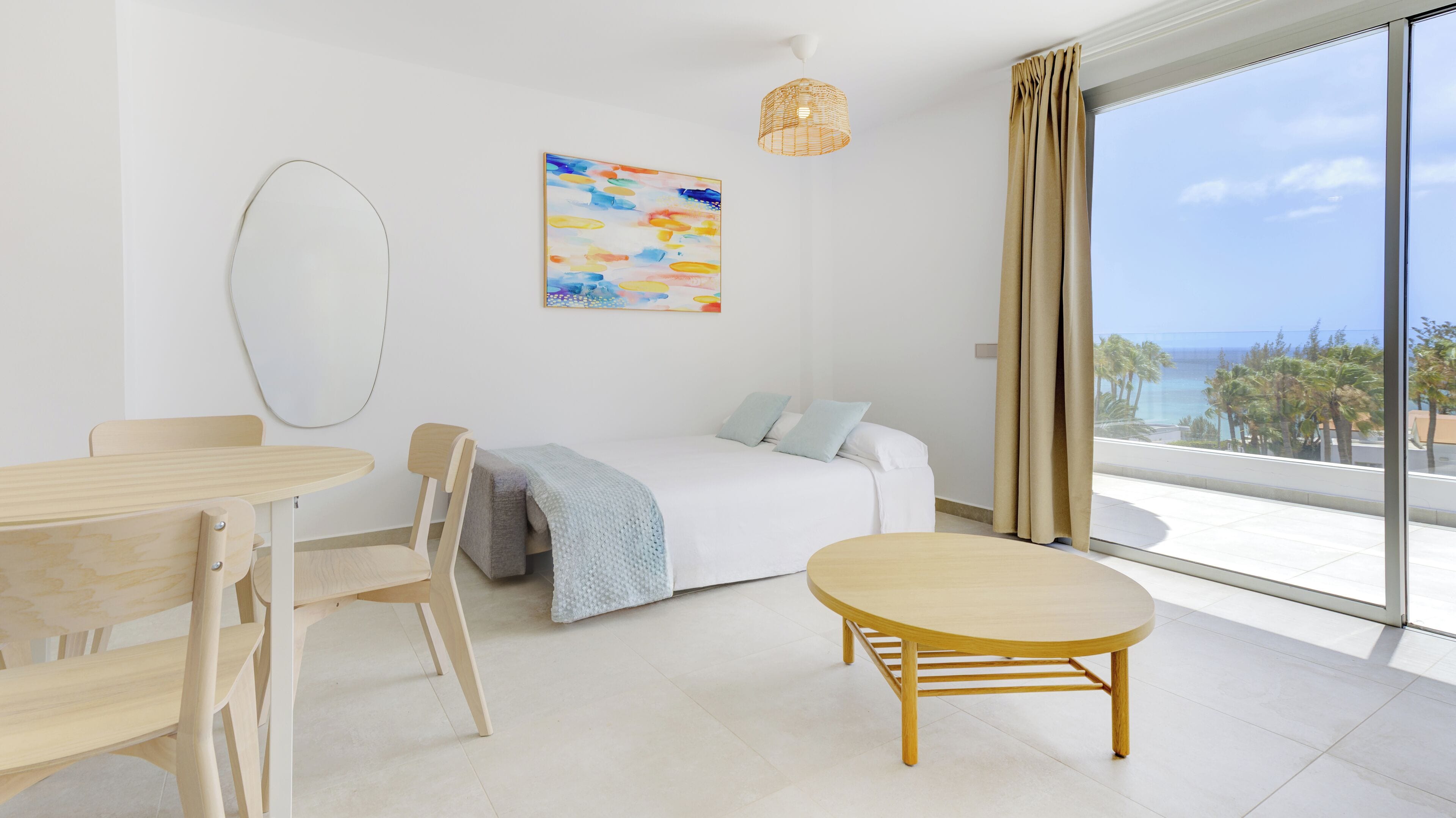A modern bedroom with a large window, a bed, a round table, and a chair.