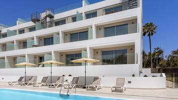 Una piscina al aire libre, sillones reclinables de piscina