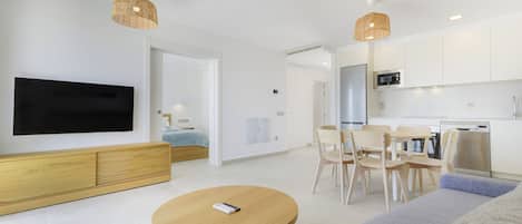 A modern living room with a flat-screen TV, wooden furniture, and a dining area with chairs and a table.