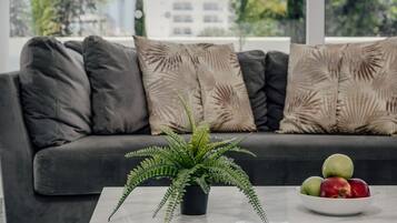 A modern living room with a grey sofa, a white coffee table, and a potted fern.