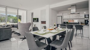 Een moderne eethoek met een witte tafel gedekt voor vier personen, omringd door grijze stoelen.