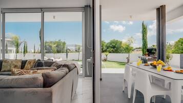 A modern living room with a sofa and a glass dining table.