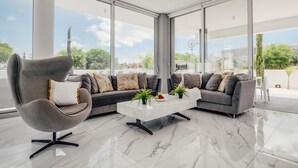 Een moderne woonkamer met een grijze bank, een witte salontafel en een grijze fauteuil.