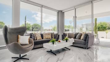 Una sala de estar moderna con un sofá gris, una mesa de centro blanca y un sillón gris.