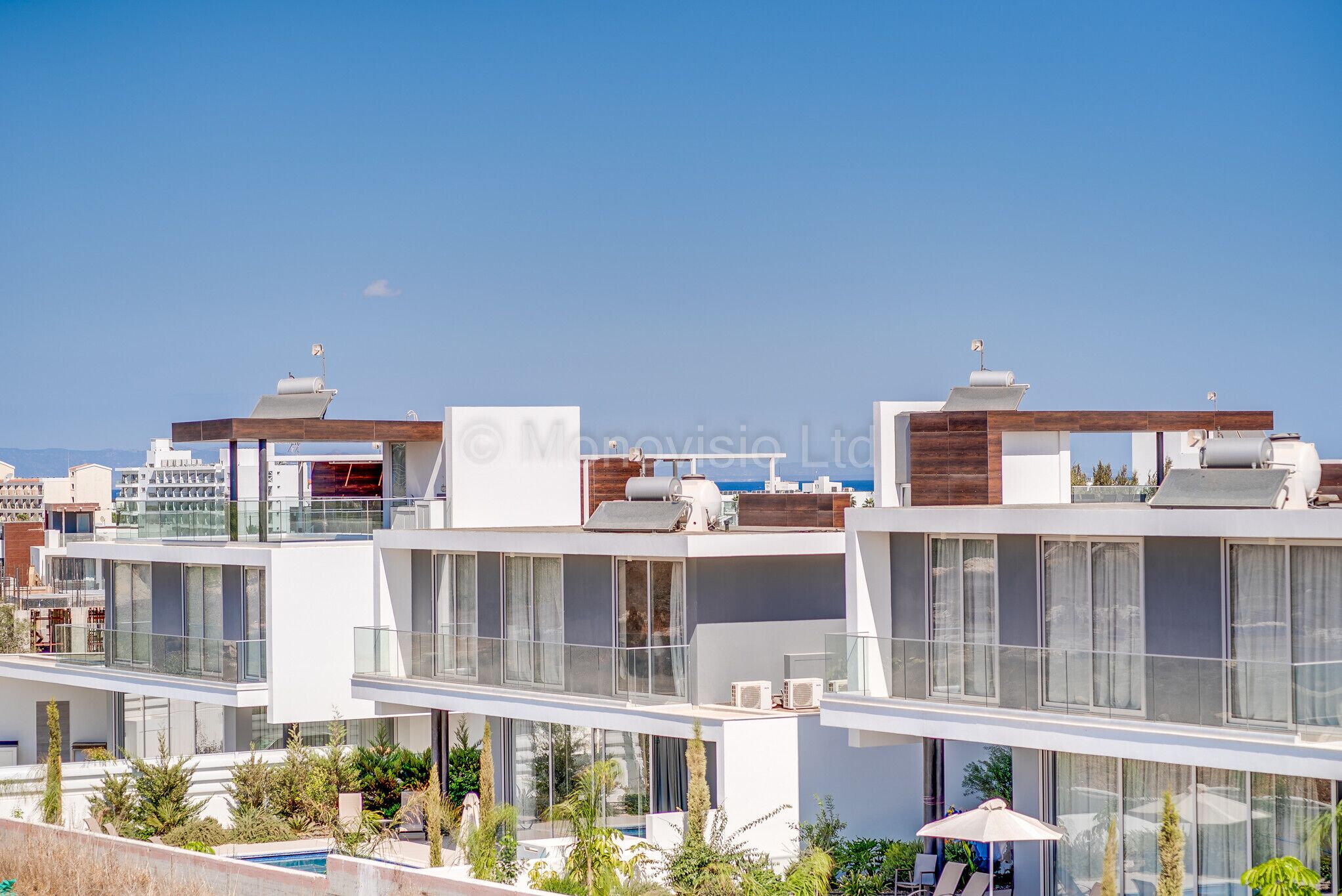 A modern multi-story residential building with balconies, large windows, and a pool area.