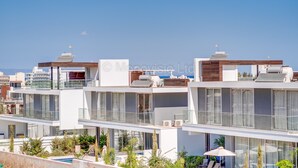 Un immeuble résidentiel moderne à plusieurs étages, doté de balcons, de grandes fenêtres et d’un espace piscine.
