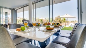 Un coin repas avec une table mise pour le petit-déjeuner, de grandes fenêtres et une vue sur l’extérieur.
