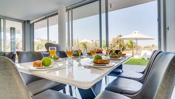 A dining area with a table set for breakfast, large windows, and a view of the outdoors.