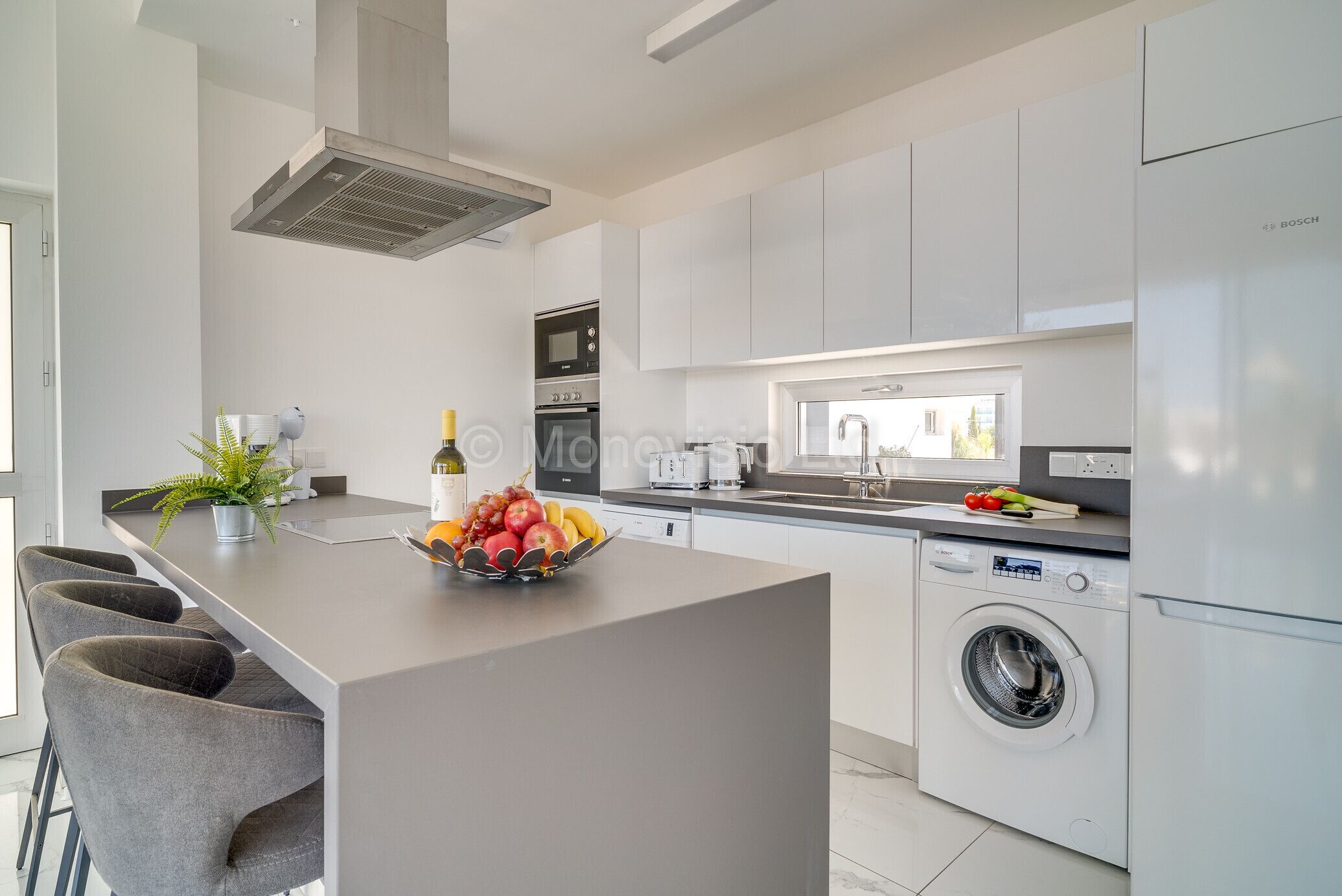 A modern kitchen with a central island, a washing machine, and a microwave.