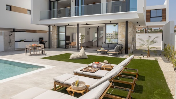 Una casa moderna de dos pisos con piscina, mobiliario exterior y césped bien cuidado.