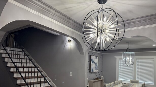 Ein modernes Interieur mit Treppe, Essbereich und einer Chandelüster.