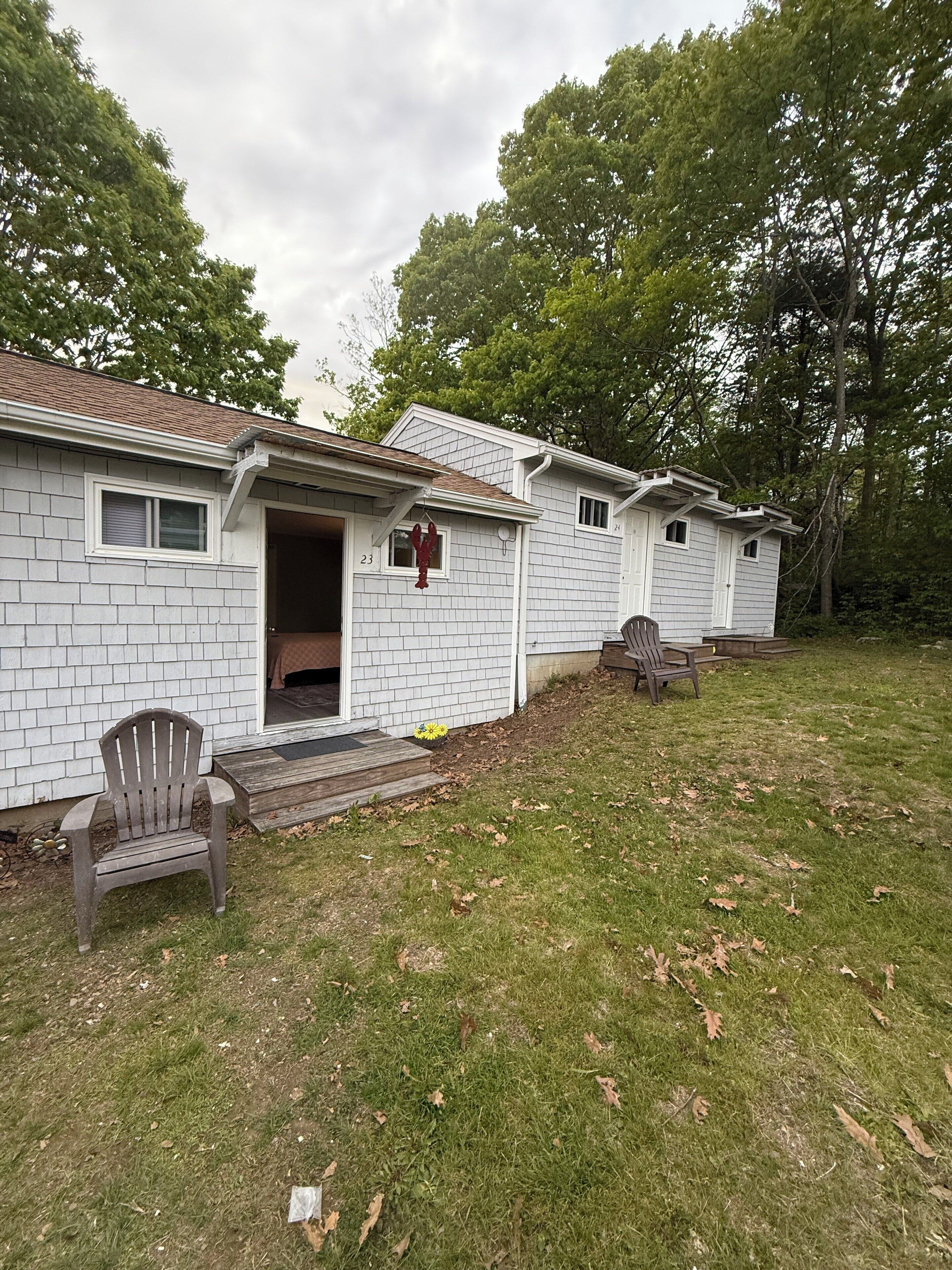 A single-story house with a front porch, a wooden chair, and a small garden area.