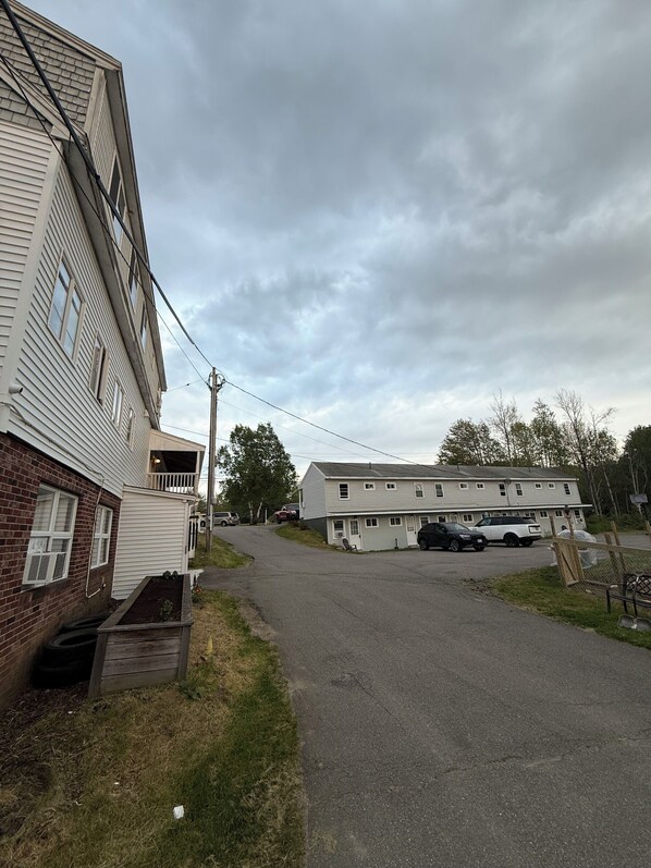 A two-story building with a flat roof, a front porch, and a driveway leading to a parking area.
