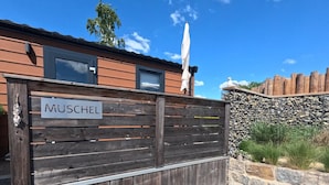 A wooden gate with a sign that reads "MUSCHEL" in front of a building with a stone wall and a wooden fence. - Shell on the Rhön beach with whirlpool (Wartmannsroth)