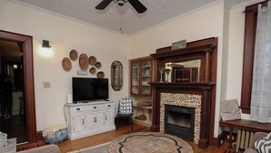 A living room with a fireplace, a television, and a round coffee table. - Historic Main Street Getaway (Leola)