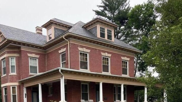 A large, two-story brick house with a covered porch and a well-maintained lawn. - Historic Main Street Getaway (Leola)