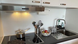 Ett modernt kök med en spis, en diskho och en skål med frukt på bänkskivan.