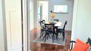 Un comedor con suelo de madera, una mesa con sillas y una alfombra.