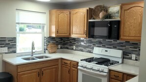 Una cocina moderna con armarios de madera, estufa a gas, microondas y un lavamanos.