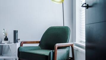 A modern room with a green armchair, a floor lamp, a white console table, and a radiator.