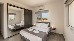 Een moderne hotelkamer met een groot bed, een spiegel, een nachtkastje met een lamp en uitzicht op het woestijnlandschap.